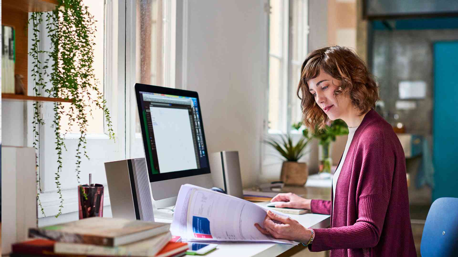 A business owner reviewing documents while on her computer, embodying the focus and organization of an asynchronous work culture.