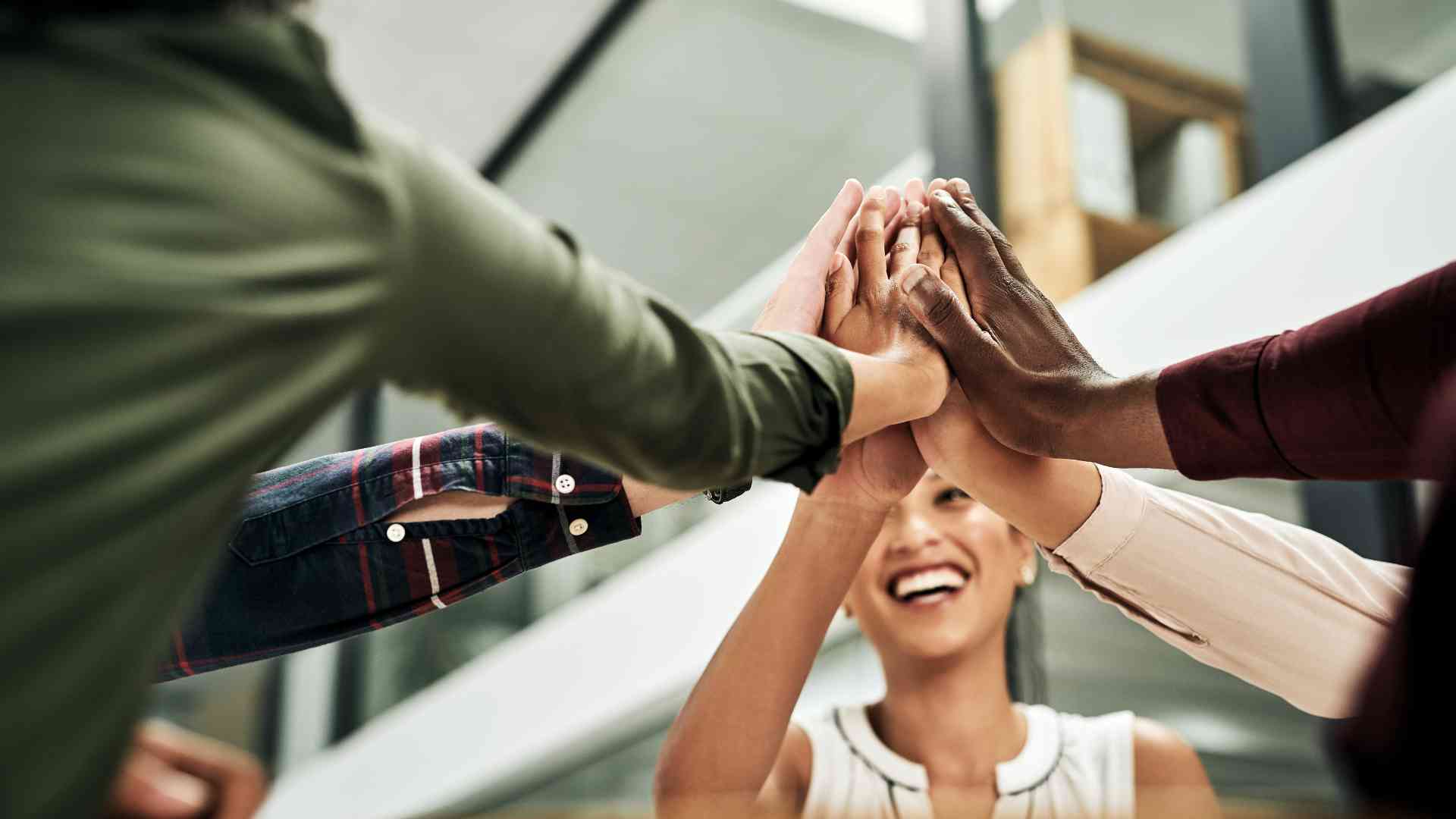 A team reaching their hands, symbolizing collaboration and how outsourcing non-core tasks solves bottleneck problems in import-export operations.