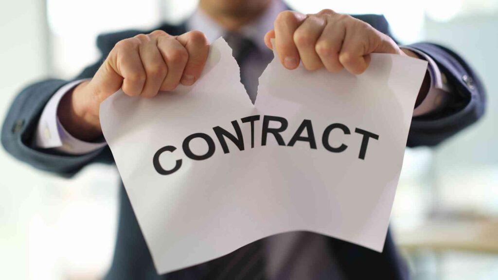 A hand ripping a contract in half, symbolizing the termination of a virtual assistant agreement.