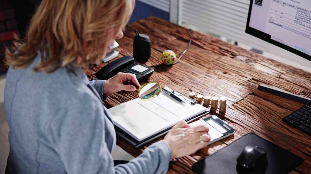 woman holding magnifying glass and looking at data closely